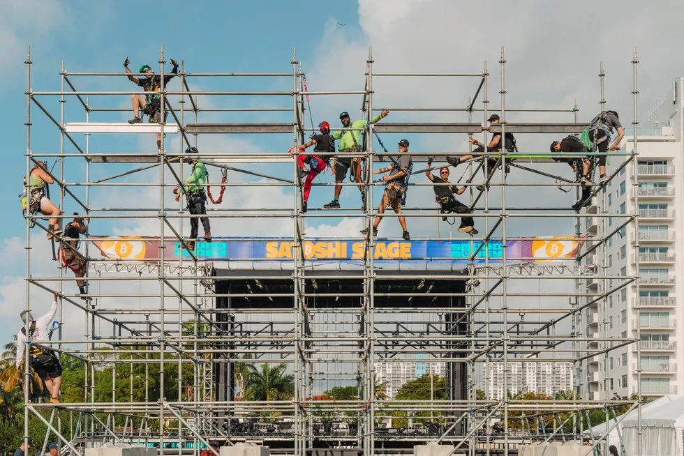 Anleggsarbeidere legger siste hånd på et stillas utenfor Miamis største konferansesenter mandag formiddag på Miami Beach. Scenen er oppkalt etter Satoshi Nakamoto, den mystiske og fremdeles ukjente personen eller gruppen som oppfant verdens største kryptovaluta.