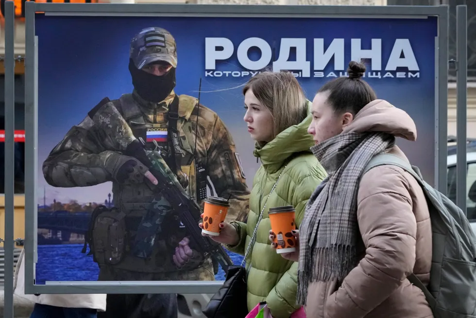 Vestens økonomiske sanksjoner mot Russland har hittil hatt begrenset effekt på landets økonomi, konstaterer eksperter. Her passerer to jenter en gateplakat i St. Petersburg med bilde av en russisk soldat og teksten «Vi forsvarer fedrelandet».