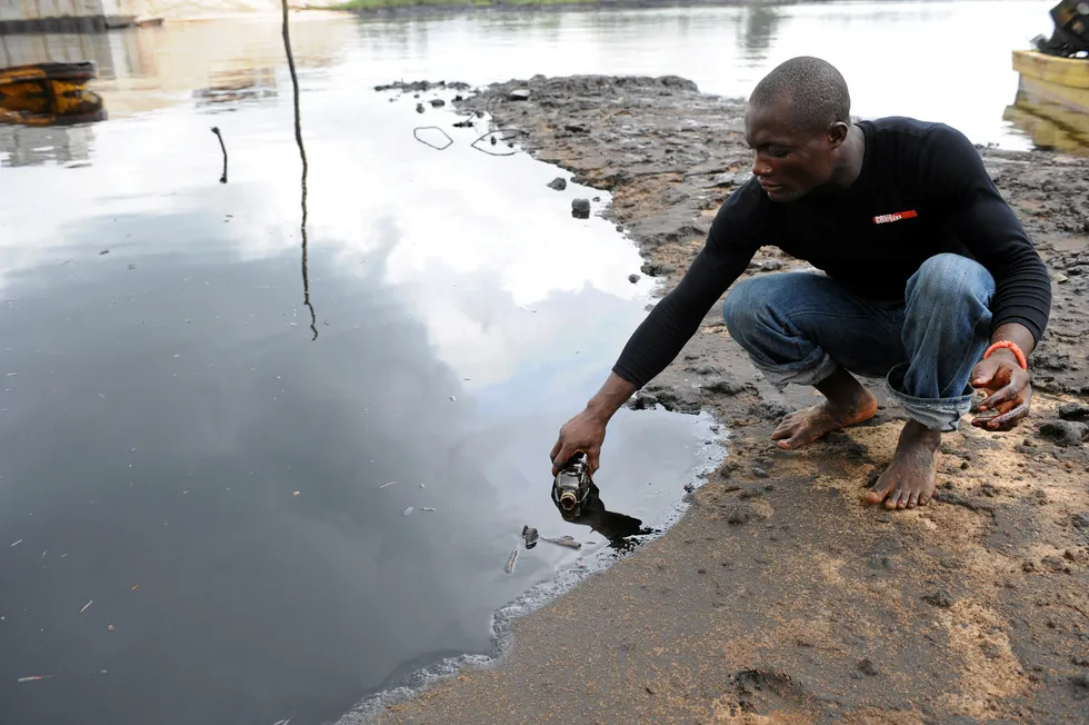 Spill: a man scoops spilled crude oil into a bottle from the waters of the Niger Delta swamps of Bodo, a village in Nigeria's producing Ogoniland region, which hosts Shell Petroleum Development Company (SPDC)