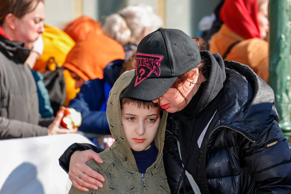 En kvinne omfavner en gutt mens de står i køen for å registrere seg som ukrainske flyktninger i Brussel.