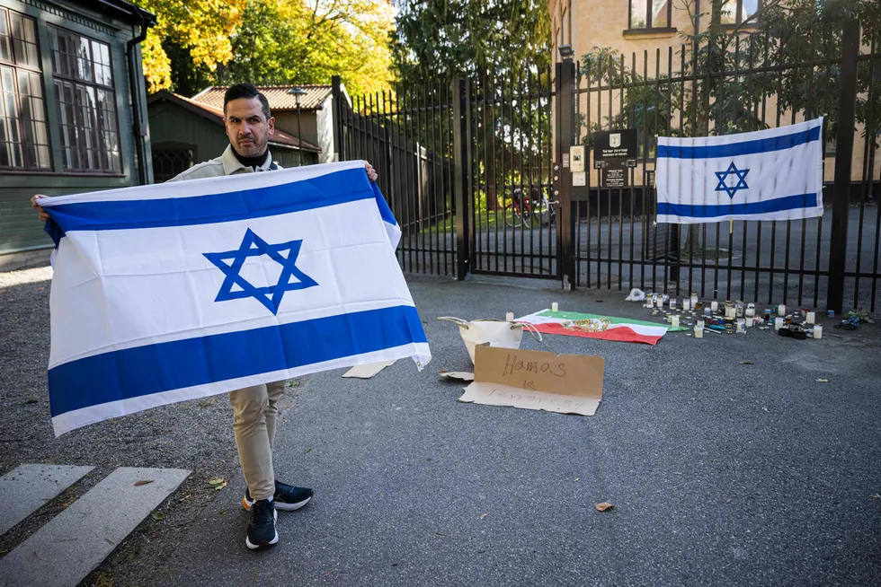 A man holds a flag of Israel to show his solidarity and support outside the Israeli embassy in Stockholm, Sweden, on 9 October 2023, after the surprise attack by Palestinian militant group Hamas against Israel.