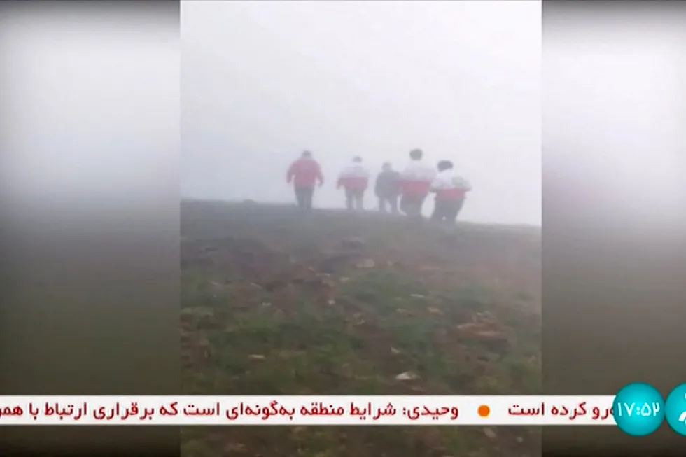 Redningsarbeidere på vei mot ulykkesstedet preget av regn og tåke. Bildet er fra iransk tv, Irinn.