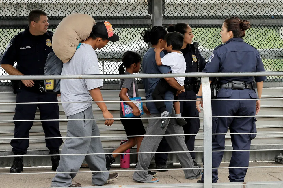 En honduransk familie eskorteres tilbake over grensa mot Mexico av amerikansk grensepoliti. Familien sa de fikk beskjed om at de ville bli skilt fra barna og valgte å frivillig dra tilbake til Mexico. Foto: AP / NTB scanpix.