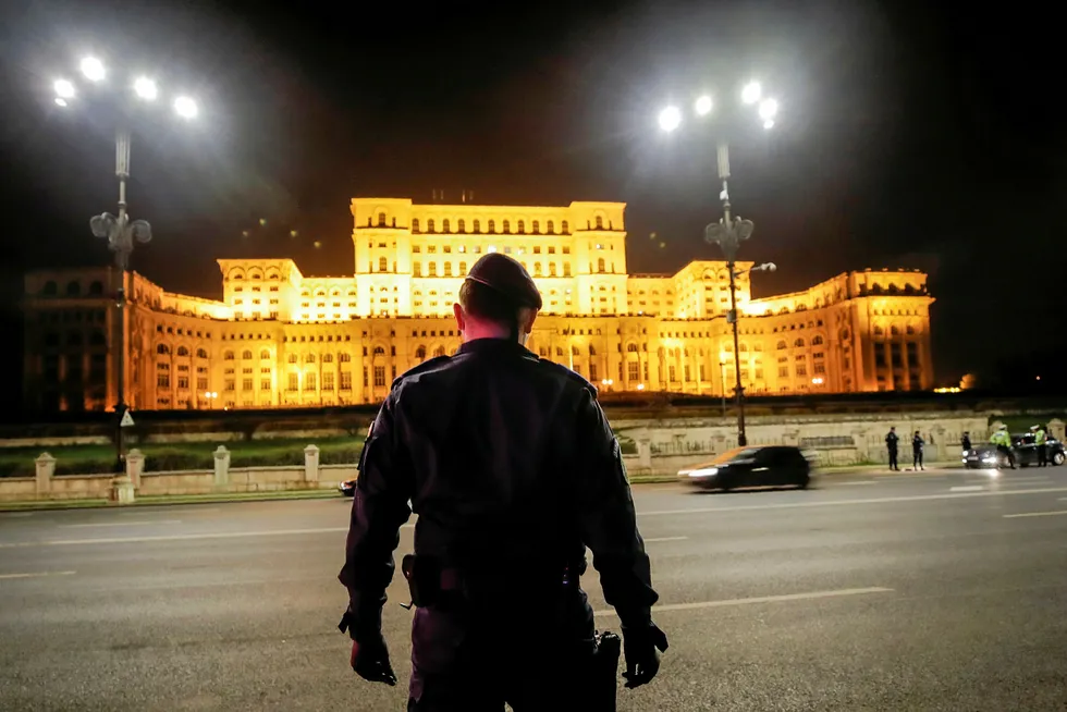 Centre point: a police officer stands outside the Romanian parliament building in Bucharest.