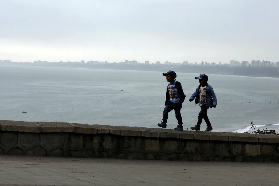 Seaview: children walk along the coast by Lima, Peru