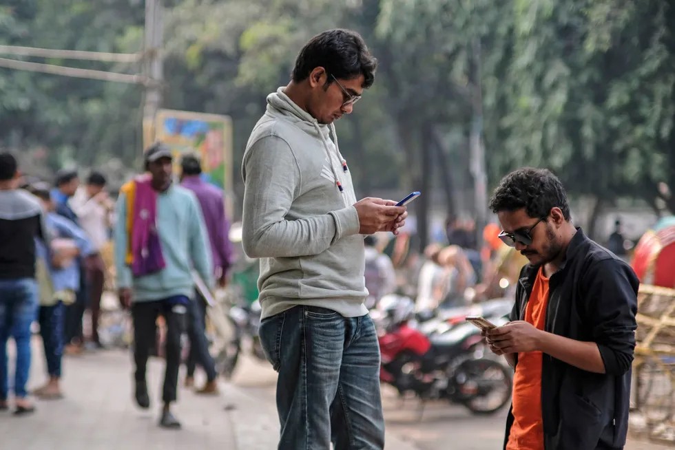 Studenter i Bangladesh med blikket rettet mot mobilen ved et universitetsområde i hovedstaden Dhaka. En kvinnelige politiker i Bangladesh dukket nylig opp i bikini i en forfalsket video.