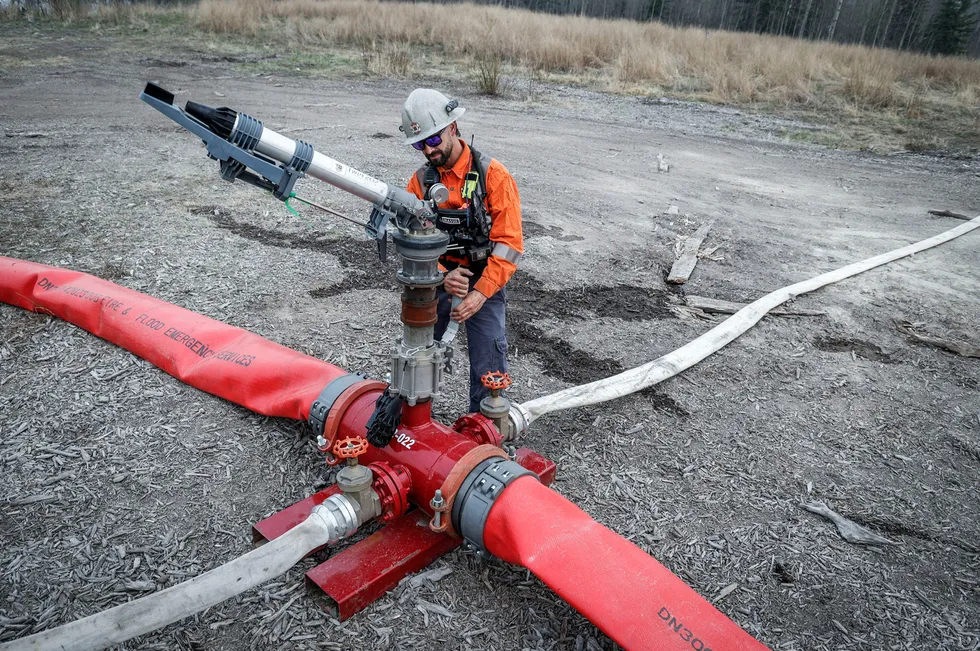 A specialist adjusts a valve on a wildfire suppression water cannon near Gregoire Lake Estates southeast of Fort McMurray, Alberta, Canada.