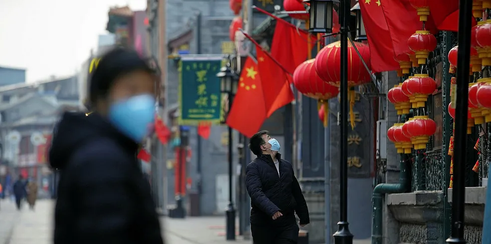 A Chinese man wears a protective mask as he stands at commercial street on February 25, 2020 in Beijing, China.