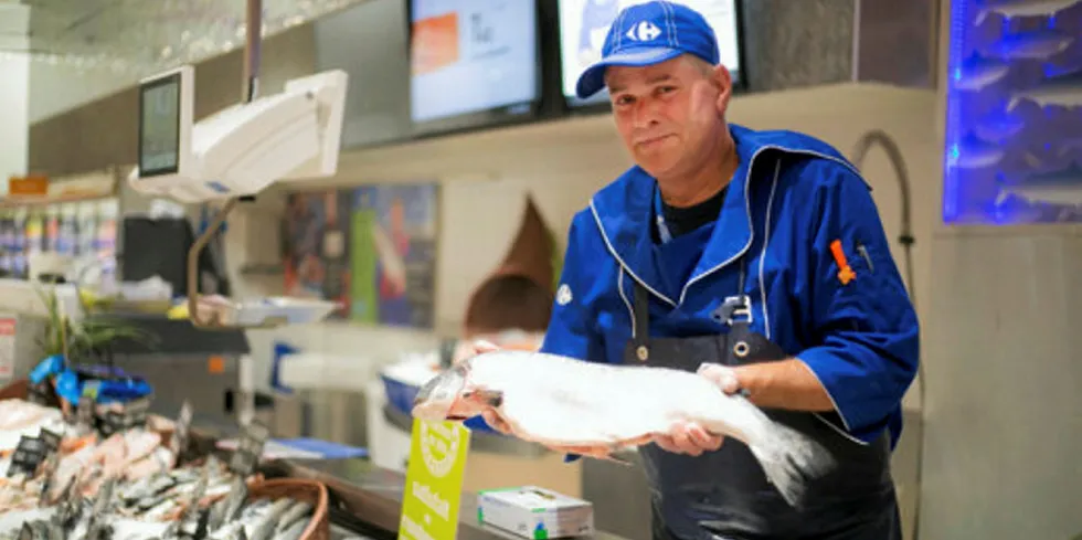 En butikkmedarbeider selger laks i ferskvaredisken til den franske butikkjeden, Carrefour.