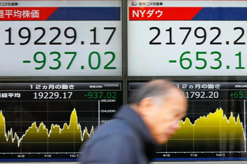 En mann passerer skjermer som viser fallet på den japanske børsen i Tokyo første juledag.