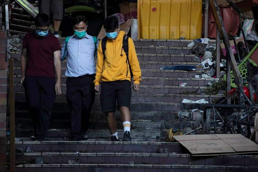 En rektor følger to ungdommer ut fra Hongkongs tekniske universitet. Om lag hundre demonstranter skal være igjen inne på området. Foto: Ng Han Guan / AP / NTB scanpix