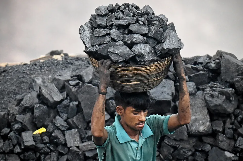 A coal picker carries coal from an open cast mining site on the outskirts of the city of Dhanbad, eastern India, earlier this month.