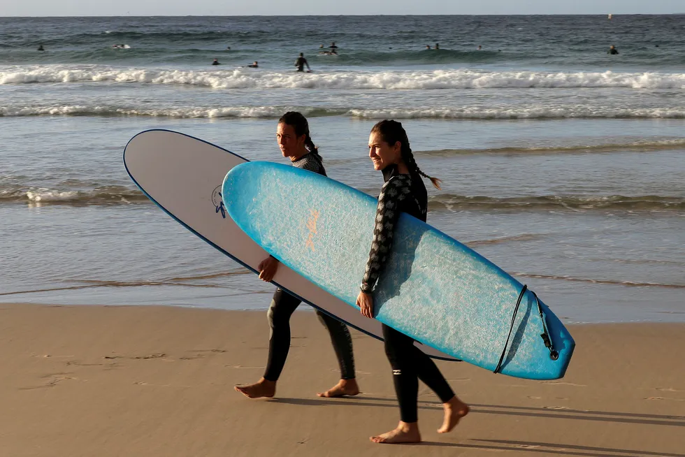 Surfere på vei ut i vannet på Bondi Beach i Sydney. Stranda har til nå kun vært åpen for at surfere og svømmere kan trene, men fredag åpnes strendene for hele befolkningen i New South Wales.