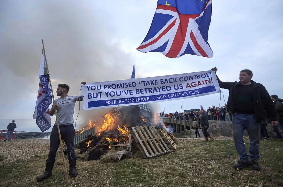 Demonstranter foran brennende båt på et bål langs kysten under demonstrasjonen i Whitstable, sørøst i England 8. april. Foto: Niklas Hallen/AFP/NTB Scanpix