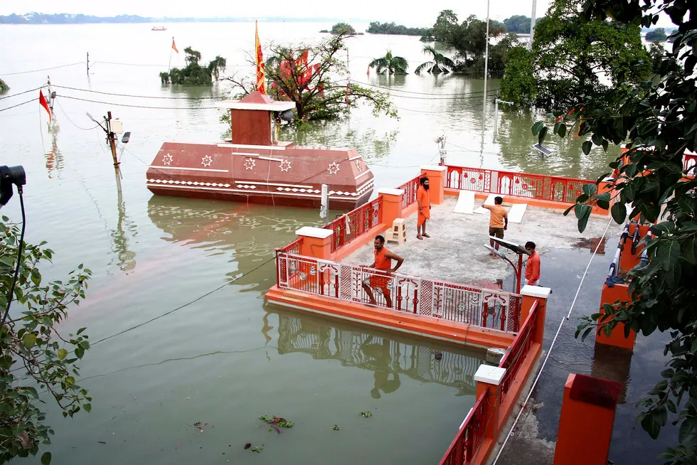 Mange er døde etter store oversvømmelser i India. På bildet står prester på taket av et oversvømmet tempel nær Sangam i Allahabad.