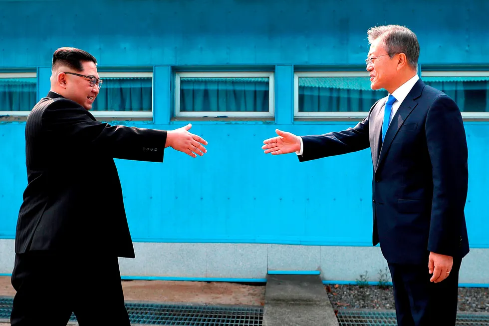 Nord-Koreas leder Kim Jong Un (t.v.) hilser på Sør-Koreas president Moon Jae-in over grenselinjen.