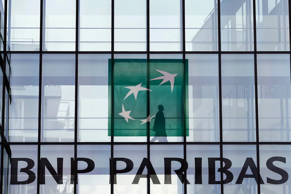 Credit lines: An employee walks behind the logo of BNP Paribas in a company's building in Issy-les-Moulineaux, near Paris.