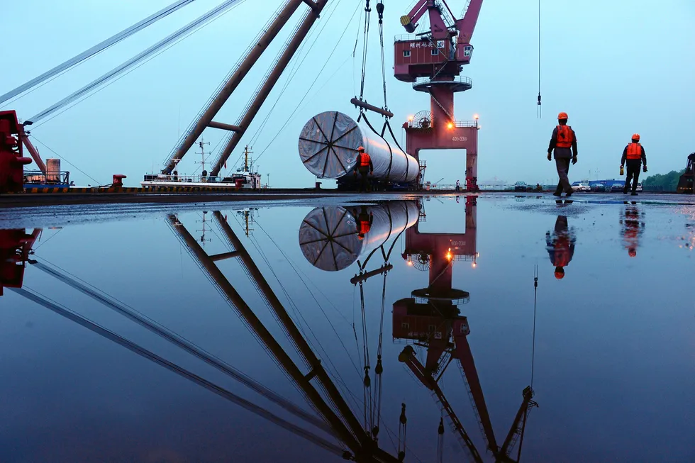 Heavy lift: workers near a crane lifting offshore wind energy equipment at a port in Nanjing, in China's Jiangsu province