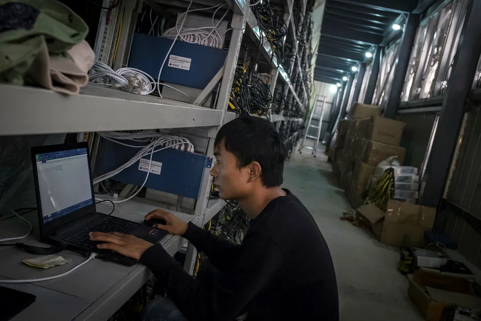 En mann kobler en bitcoin-utvinningsmaskin til internett ved en bitcoin-gruve i Kina, hvor rundt 75 prosent av utvinningen skjer. Foto: AP/Chinatopix/NTB Scanpix
