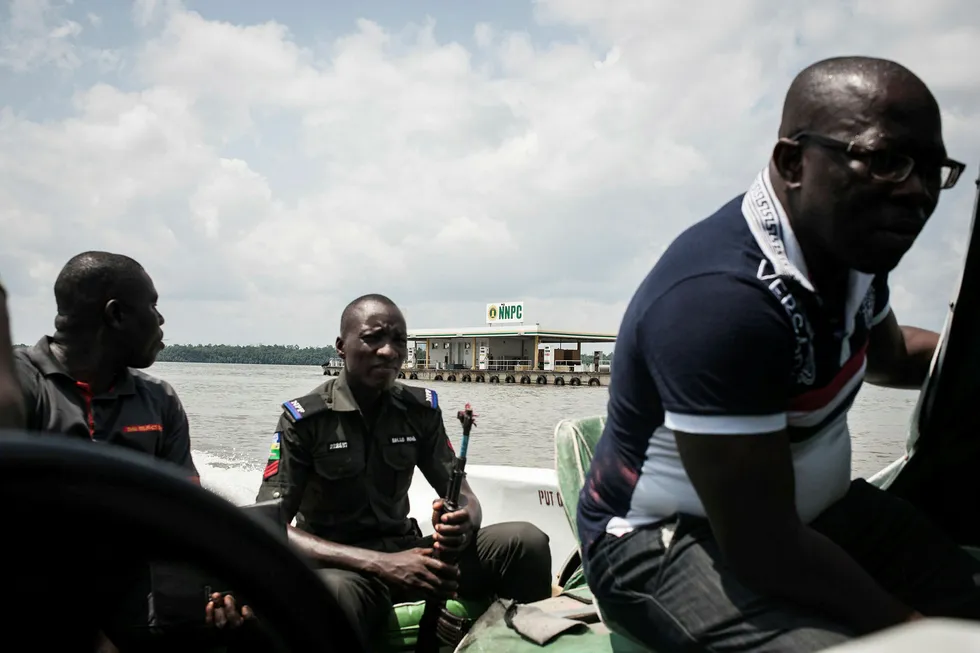 Insecurity persists: a member of the Nigerian Police Forces sits in a boat as passing by a floating petrol station near Okerenko in Gbaramatu Kingdom, Warri South-West Local Government, Delta State in June 2016