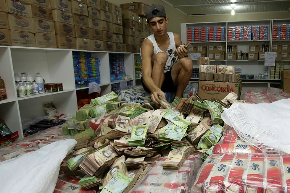 Butikker i Venezuela kan få inn så store mengder med sedler at de har gitt opp å telle dem og begynt å veie dem i stedet. Mannen i denne dagligvarebutikken i Pacaraima ser imidlertid ut til å gjøre et forsøk på manuell telling. Foto: William Urdaneta/Reuters/NTB scanpix