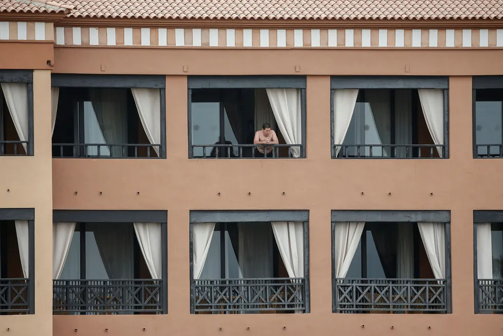 En mann står på balkongen til hotellrommet sitt på H10 Costa Adeje Palace Hotel, hvor flere personer er satt i karantene som følge av at fem personer er bekreftet smittet av koronaviruset.