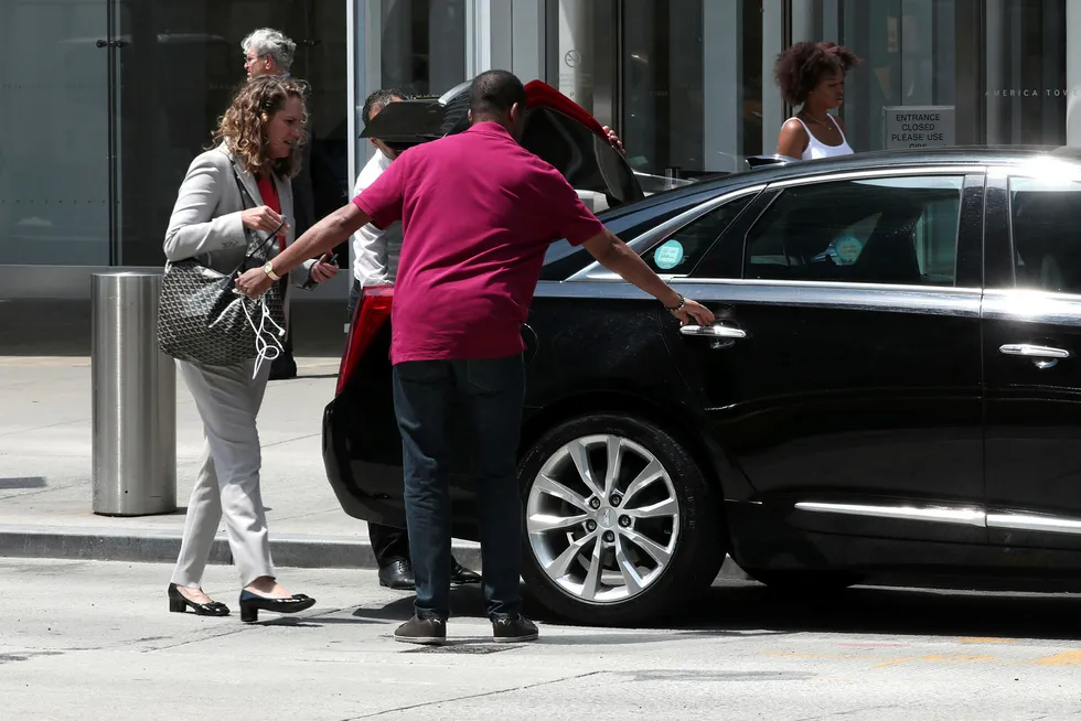 En sjåfør fra et delingsøkonomiselskap hjelper en passasjer inn i en bil på 6th Avenue i New York City.
