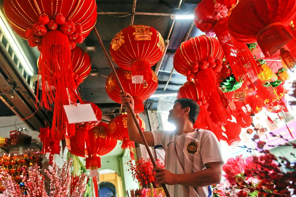Preparing for festivities: a vendor adjusts traditional lanterns for sale during Lunar New Year celebrations in Kuala Lumpur, Malaysia