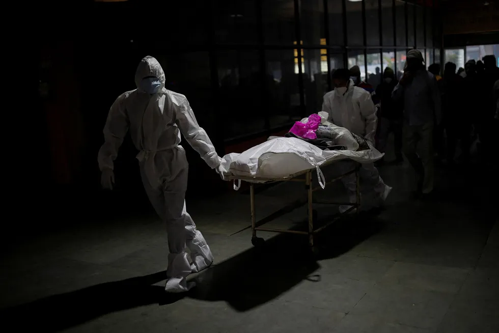 Helsearbeidere frakter liket til en 55 år gammel mann som er død som følge av koronaviruset rett før han skal kremeres. Bildet er tatt i et krematorium i New Delhi den 4. februar i år.