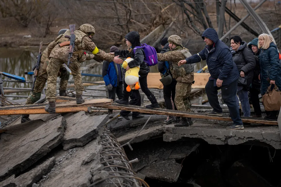 Ukrainske soldater hjelper en familie på flukt i utkanten av Kyiv lørdag.