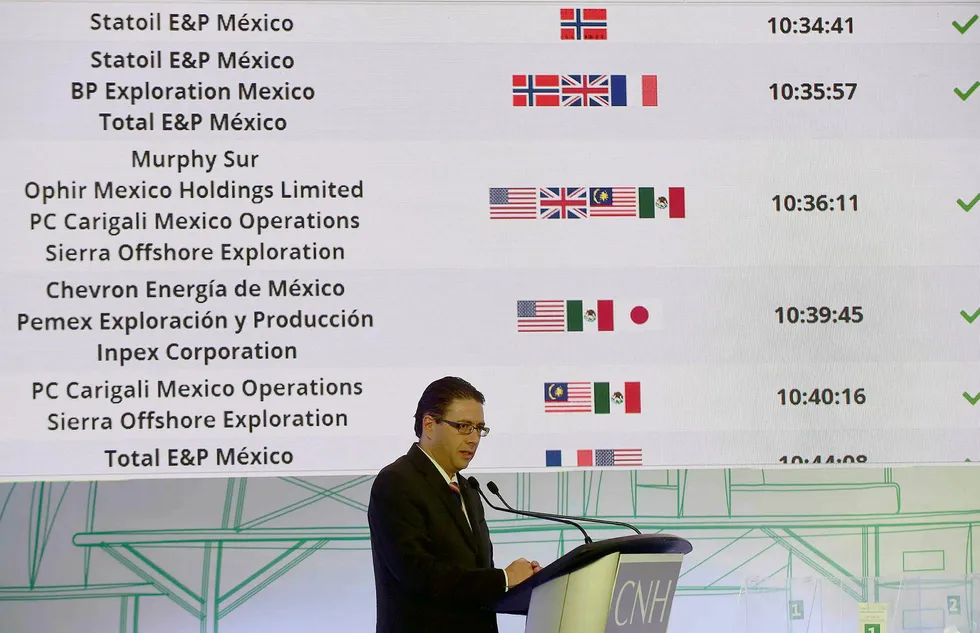 Leder av Mexicos nasjonale hydrokarbon-råd, Juan Carlos Zepeda, presenterer vinnerne i den første offentlige anbudsauksjonen på meksikansk sokkel i Mexico City mandag. Det norske flagget fyller de øverste plassene. Foto: ALFREDO ESTRELLA/AFP