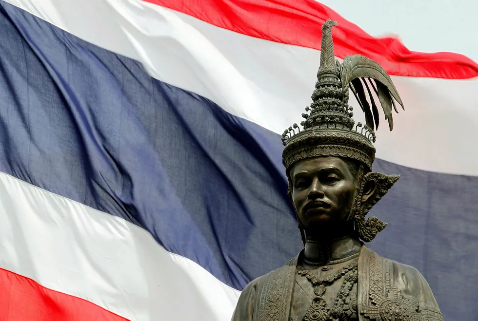 Stage set for exploration: Thailand flag behind a statue of former King Rama VII
