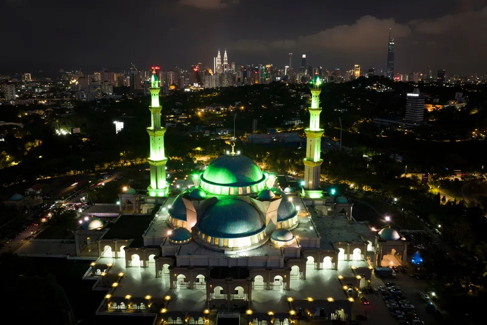 Illuminated: the Wilayah Mosque with the background of city skylines on the eve of Ramadan in Kuala Lumpur, Malaysia