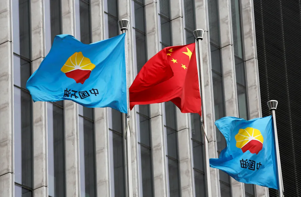 A Chinese national flag flutters between PetroChina flags at PetroChina's headquarters in Beijing