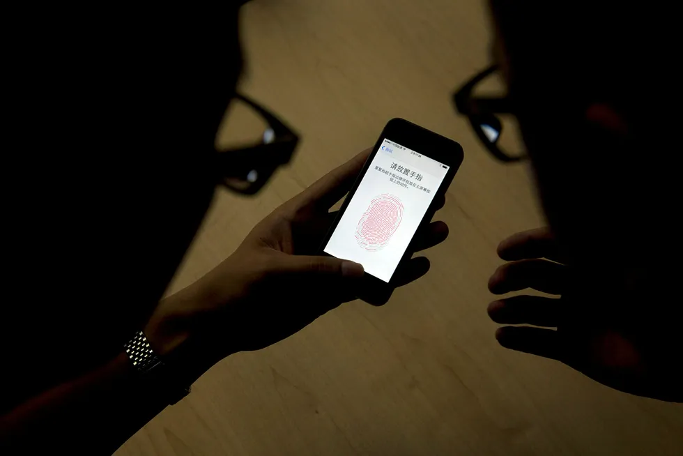 Illustrasjonsbilde. En ansatt viser frem fingerskanneren på en iPhone 5s. Nå ønsker politiet å kunne bruke tvang for å få åpnet telefoner som antas å inneholde bevis. Foto: NTB Scanpix / Ng Han Guan