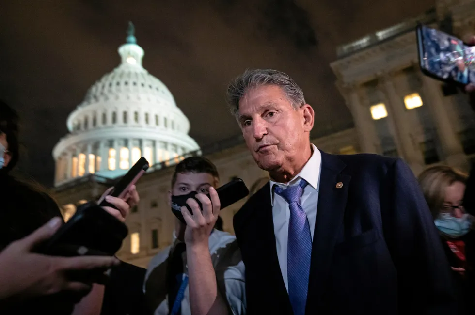 Senator John Manchin surrounded by reporters outside the US Capitol in Washington DC.