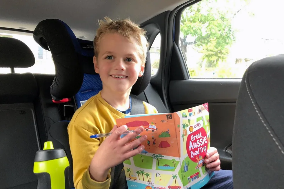 On the road: a young boy enjoys playing with his Great Aussie Road Trip booklet and collectable stickers on a long drive