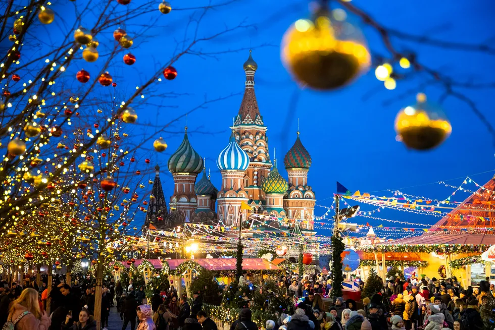 People walk in Red Square decorated for Christmas and New Year celebrations, with the St. Basil's Cathedral in the background in Moscow, Russia, Saturday, Dec. 21, 2019. (AP Photo/Pavel Golovkin)