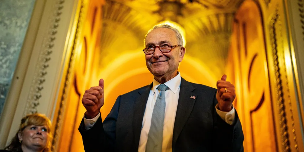 Senate Majority Leader Chuck Schumer, co-author of the Inflation Reduction Act, celebrates the passing of the bill as he emerges from the Senate chamber on Sunday.