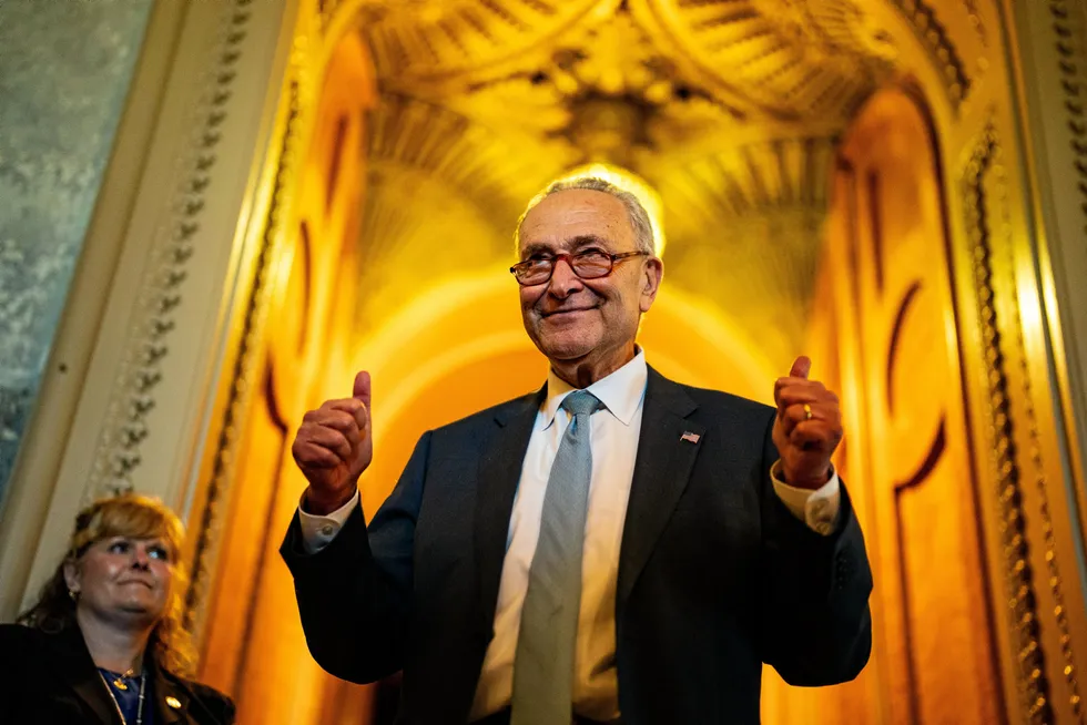 Senate Majority Leader Chuck Schumer, co-author of the Inflation Reduction Act, celebrates the passing of the bill as he emerges from the Senate chamber on Sunday.