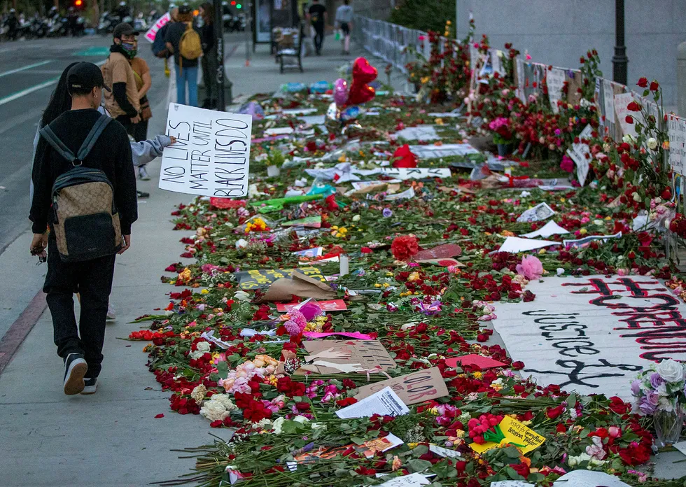 Demonstranter går forbi rettsbygningen i Los Angeles, hvor det er lagt ned blomster som symbol for støtte til de som har blitt urettferdig behandlet av politi og rettssystem.