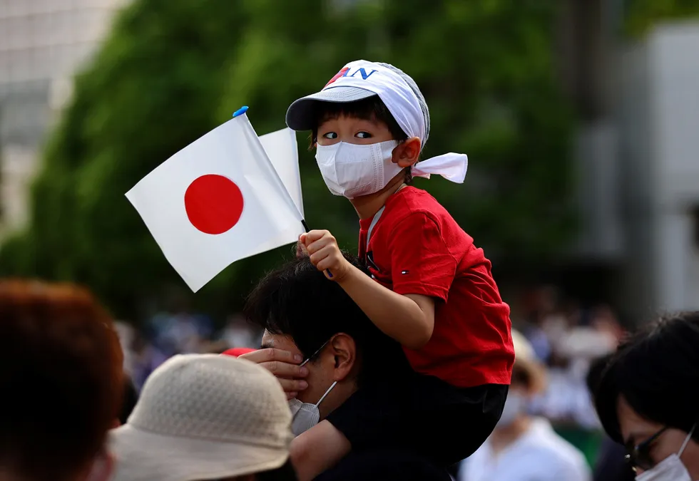 Downtown Tokyo: a boy sitting holds a Japanese flag