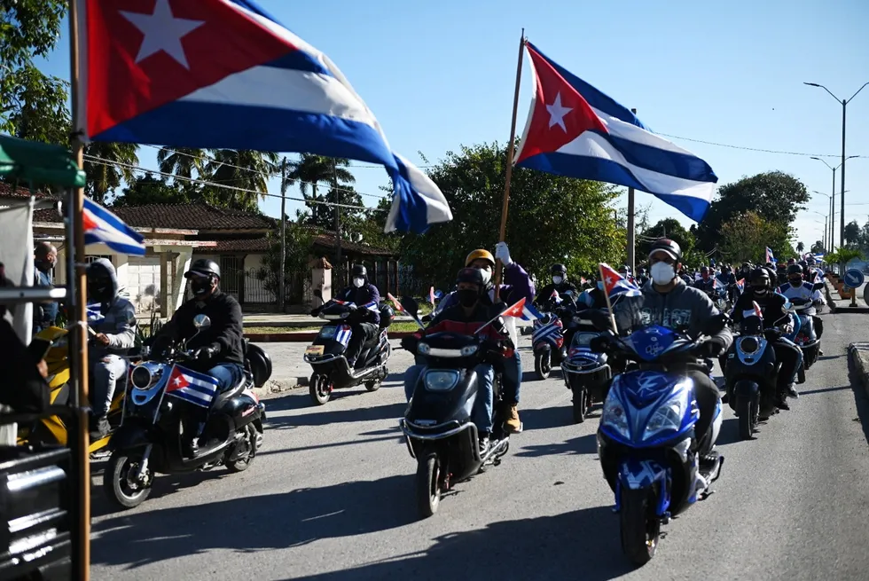 Revved up: Cubans on motorbikes waving the national flag