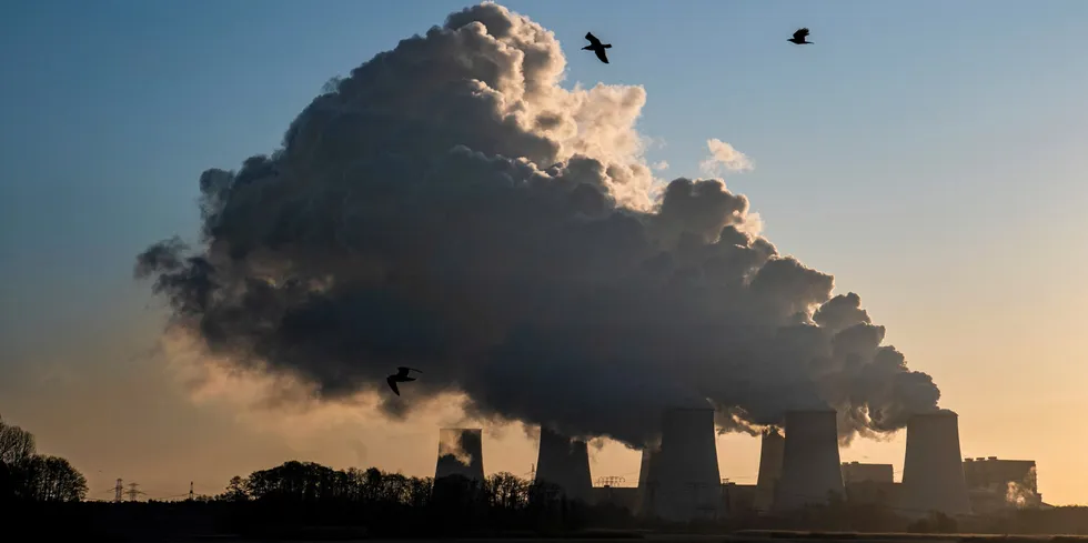 Smoke and vapor rising from the cooling towers and chimneys of a lignite-fired power station operated by LEAG.