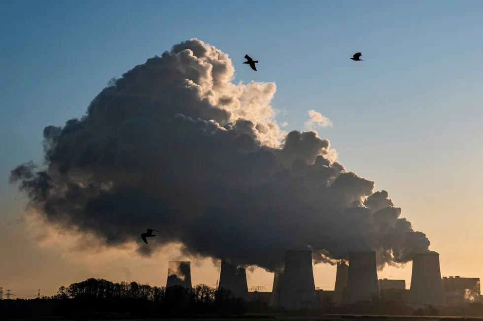 Smoke and vapor rising from the cooling towers and chimneys of a lignite-fired power station operated by LEAG.