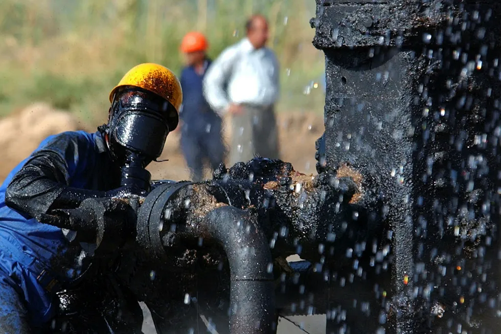 En oljearbeider prøver å stenge av en brennende oljerørledning nær en landsby utenfor Bagdad i Irak.