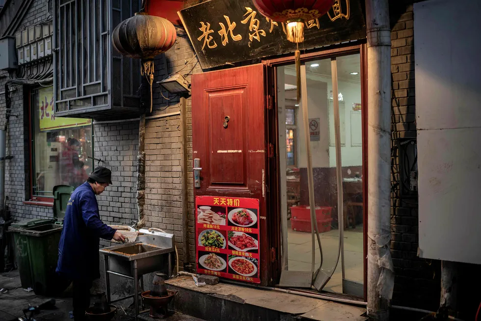 En ansatt vasker opp utenfor en restaurant i en bakgate i Beijing i januar 2020. Den første privateide restauranten i byen åpnet for 40 år siden da Kinas kommunistparti hadde startet liberaliseringen i landet.