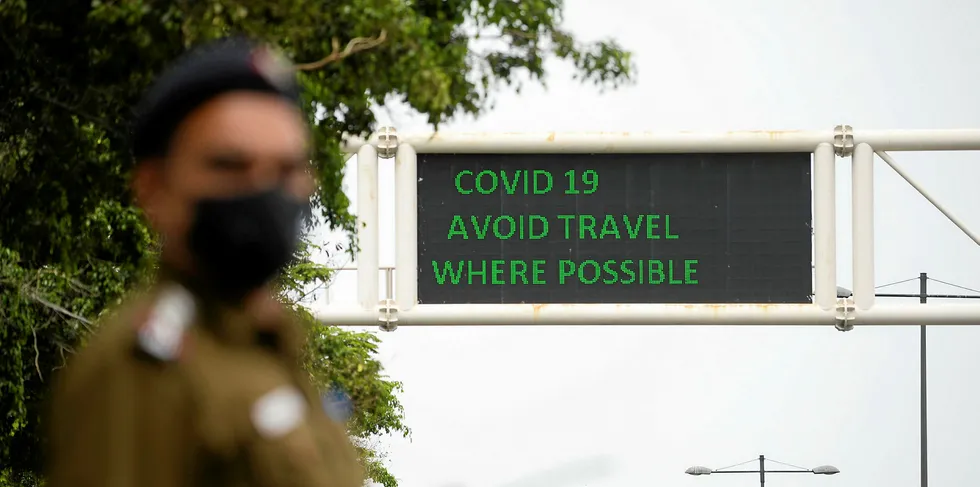 A policeman wearing a facemask stands along a roadsign informing of travel recommendations during a government-imposed nationwide lockdown as a preventive measure against the COVID-19 coronavirus in New Delhi on March 26, 2020.