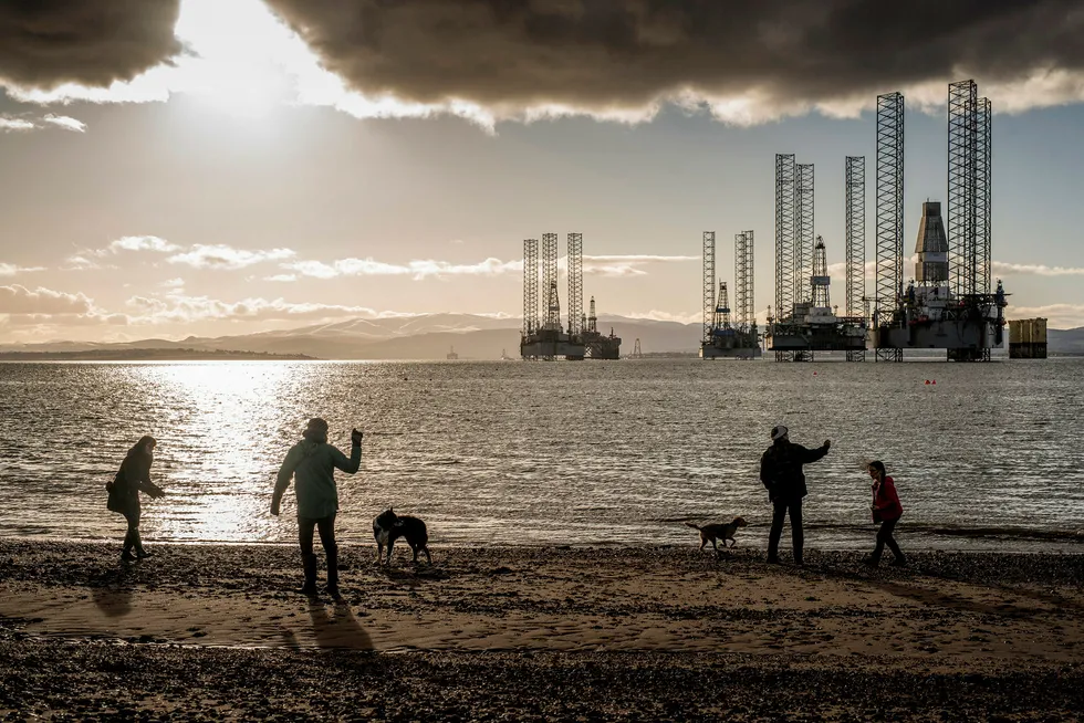 Flere rigger ligger i opplag i bakgrunnen, men folk som bor her I Cromarty i Skottland er vant til dem. Beti Bricelj, Mike Schroeder og Leon Patchett, går tur langs stranden. Foto: Tommy Ellingsen