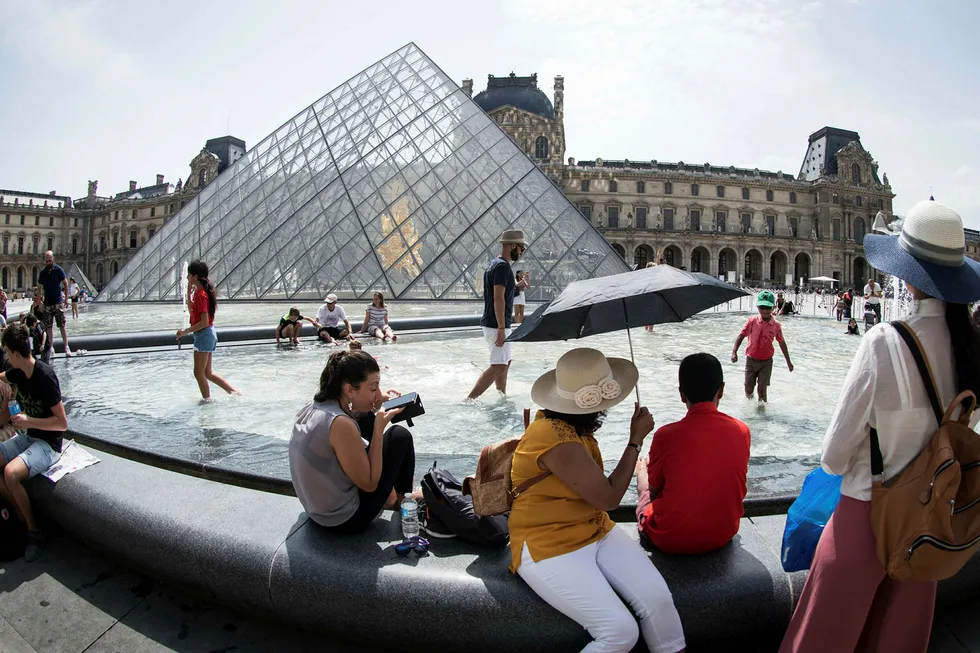 Frankrike har målt de høyeste temperaturene siden 2003. Her avkjøler turister seg ved en fontene utenfor Louvre i Paris tirsdag.